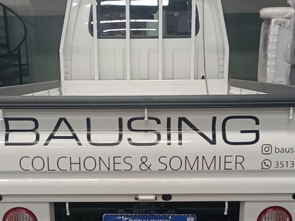 Camioneta de reparto ploteada con vinilo de corte, con el nombre de la marca en el portón trasero